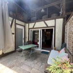 La terrasse et la porte d'entrée du logement (à gauche)